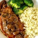 keto pork chops with mushroom sauce in a shallow white bowl with riced cauliflower and broccoli