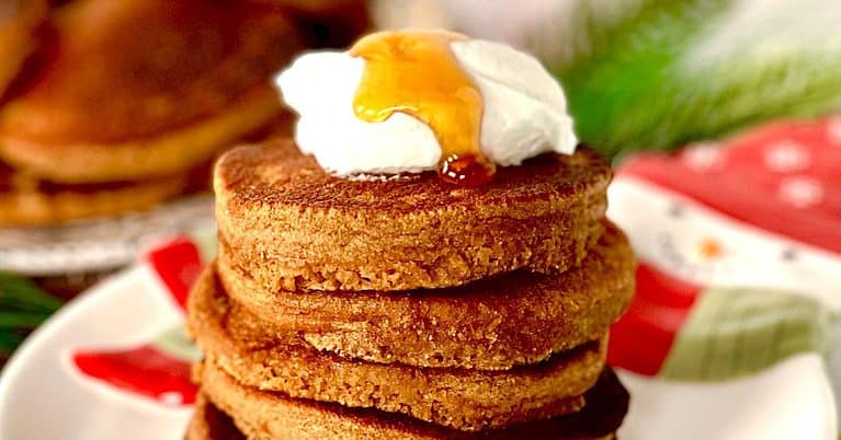 Coconut flour gingerbread pancakes stacked on top of each other, with yogurt dollops on top and maple syrup drizzled over the yogurt