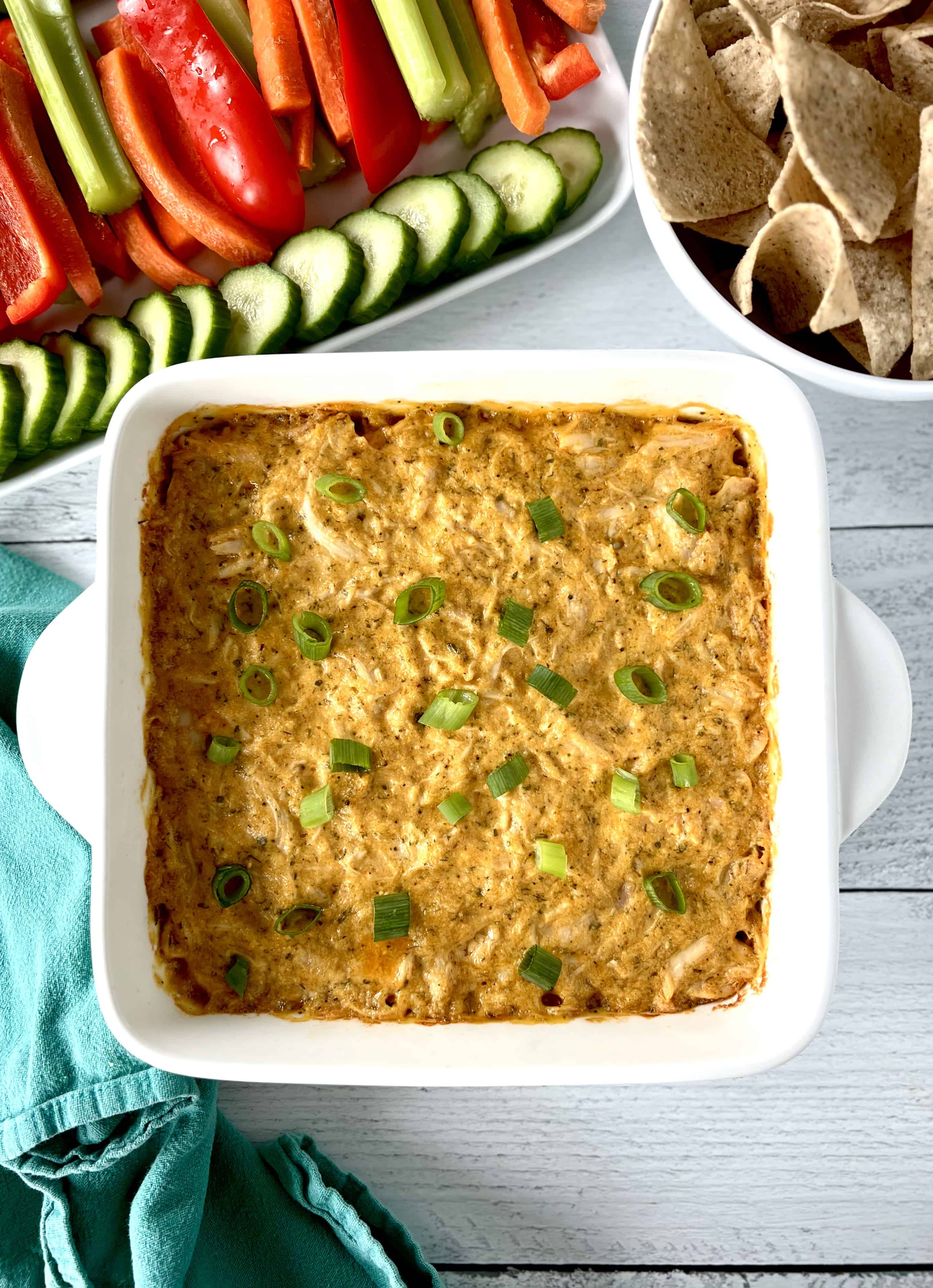 Healthy Paleo dip for veggies made with shredded chicken and hot sauce, in a white square baking dish