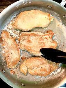 Flipping chicken in a pan.