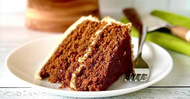 A slice of grain-free carrot cake on a white plate with a fork.