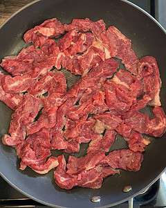 Sliced flank steak in a skillet.