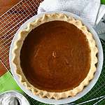 A healthy pumpkin pie on a cooling rack on a green napkin on a wooden table.
