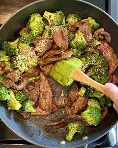 Stirring beef and broccoli in a skillet.