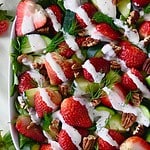 Strawberry arugula salad in a white square bowl.