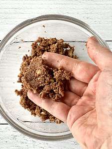 A hand holding up cinnamon streusel topping.