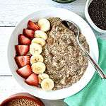 Chia seed porridge in a shallow white bowl topped with sliced bananas and strawberries.