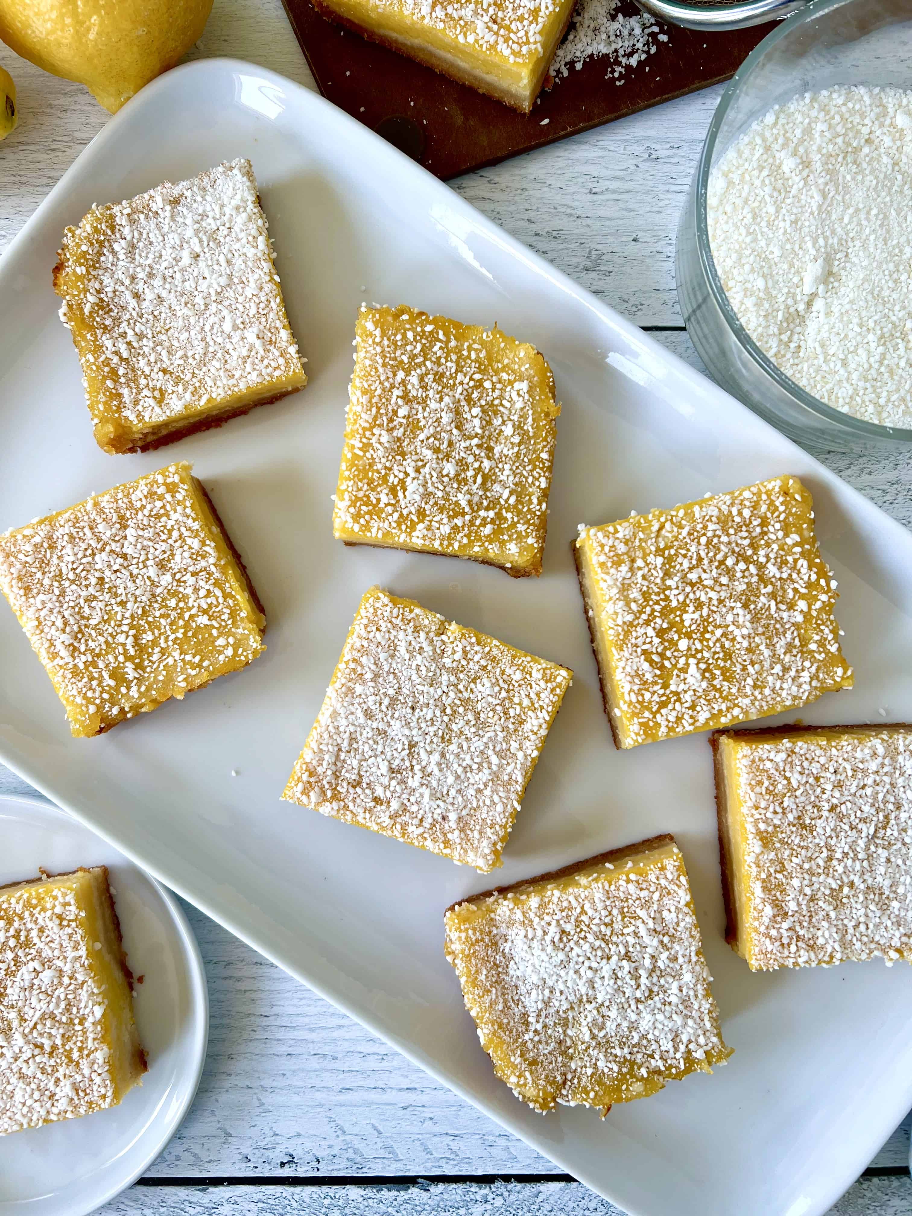 Gluten-free dairy-free lemon bars on a white rectangular platter and small white plate.