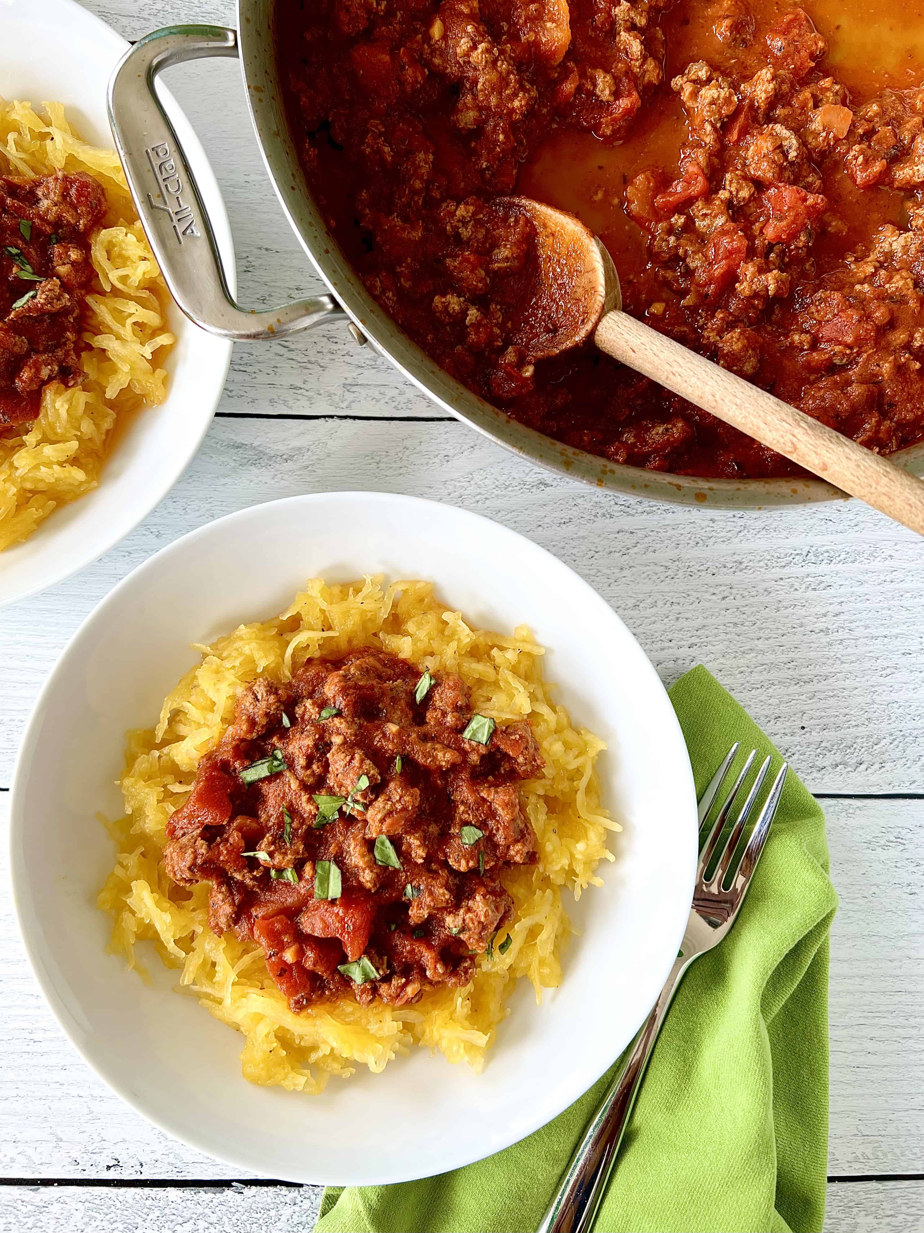 A white bowl filled with spaghetti squash topped with a ground beef marinara.