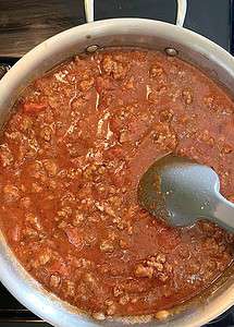 Tomato meat sauce in a stainless steel skillet.