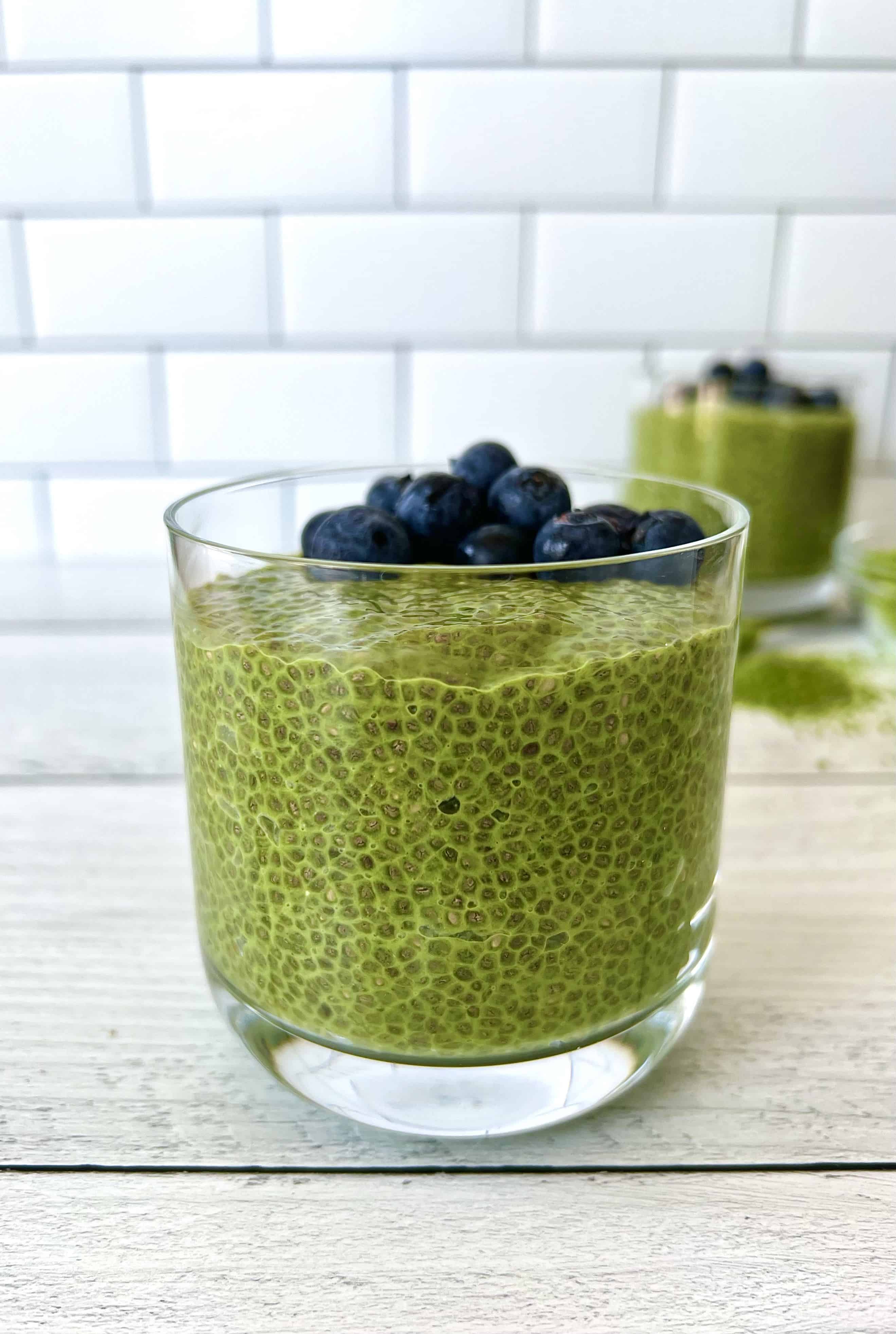 Keto chia pudding made with green tea in a glass and topped with blueberries.