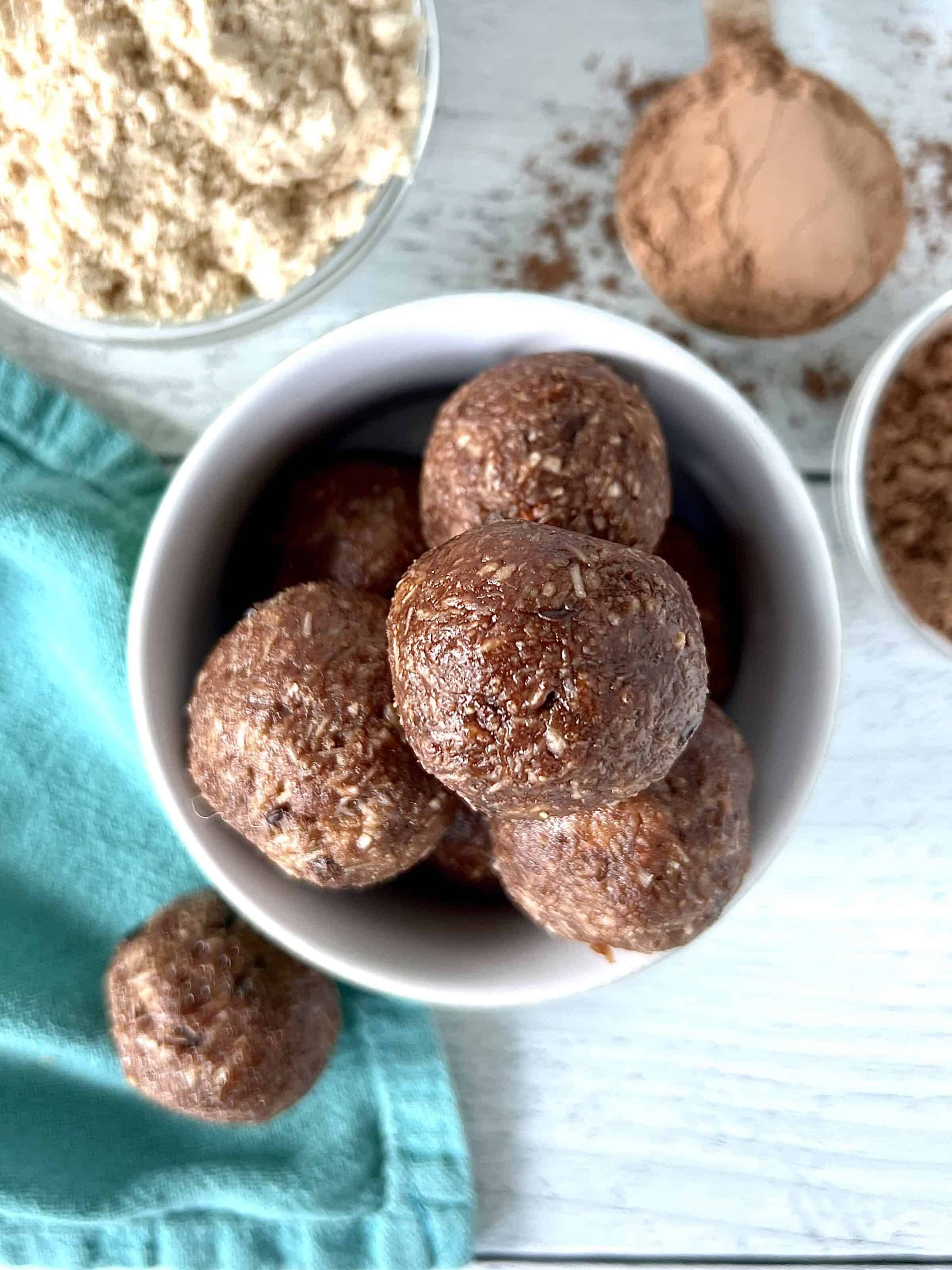no bake protein balls in a small white bowl on a white wooden table