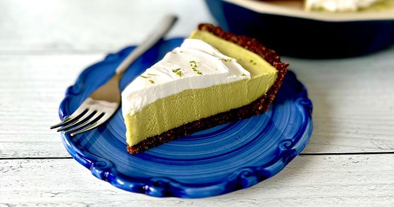 A slice of Paleo key lime pie on a blue-swirled plate with a fork.
