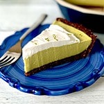 A slice of avocado key lime pie on a blue-swirled plate with a fork.