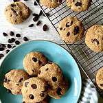 Almond flour oatmeal cookies with raisins on a cooling rack and with chocolate chips on a blue plate.