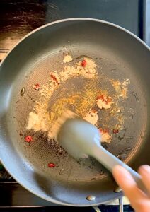 Stirring spices and tomato paste in a nonstick pan.