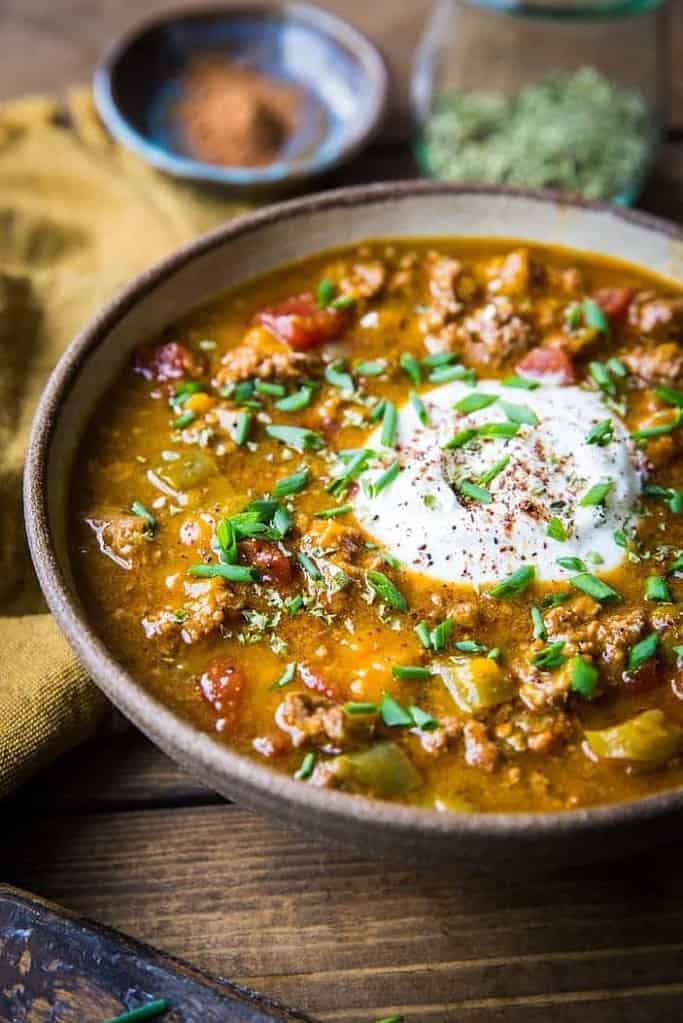 Pumpkin chili in a bowl topped with sour cream and chopped chives.