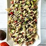 Paleo tortilla chips on a long white platter covered with nacho toppings.