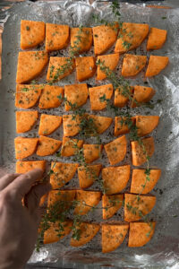 Putting thyme sprigs on sweet potatoes.