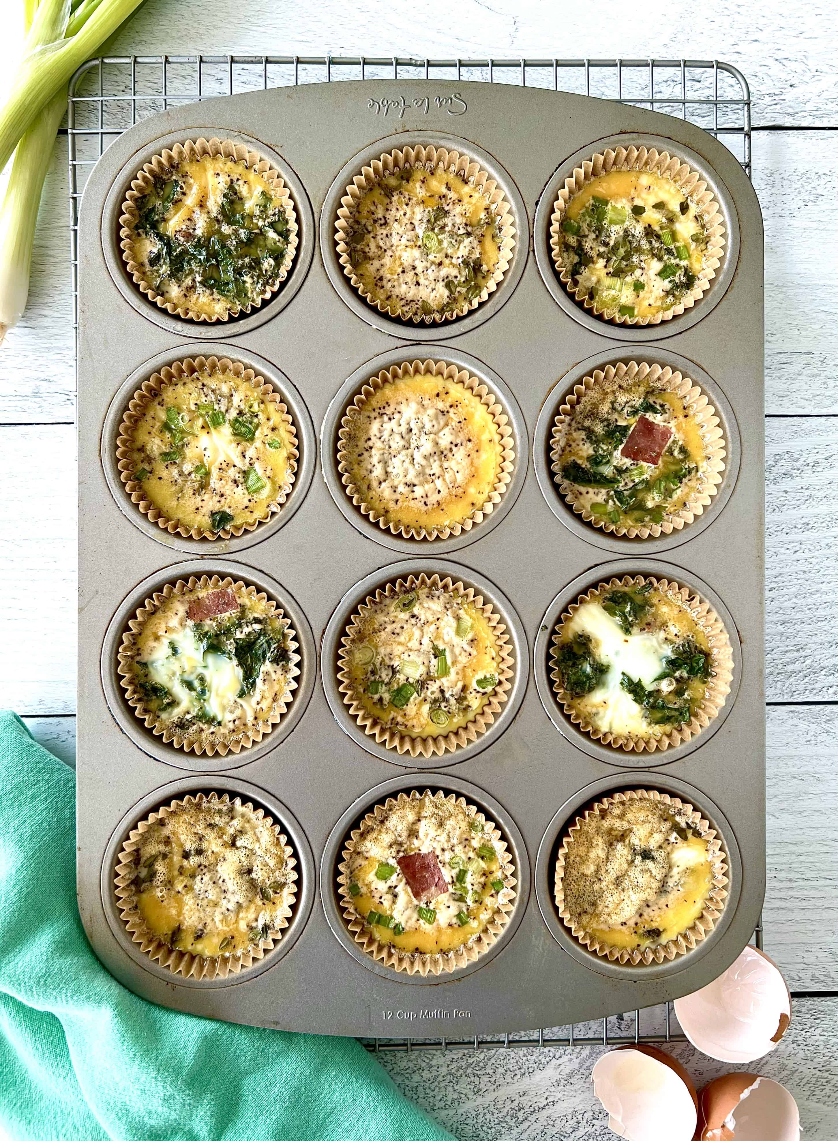 Paleo Egg Bites in muffin liners in a metal muffin pan on a cooling rack.