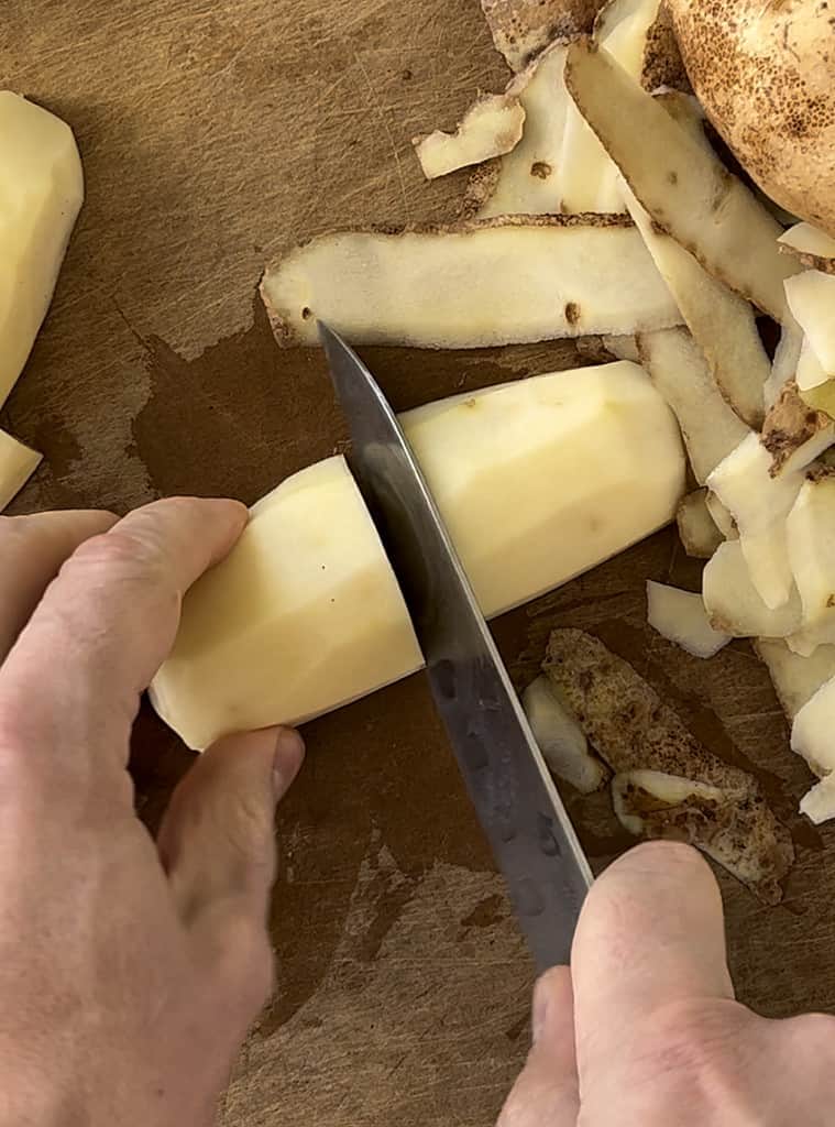 Cutting potatoes in half on a cutting board.