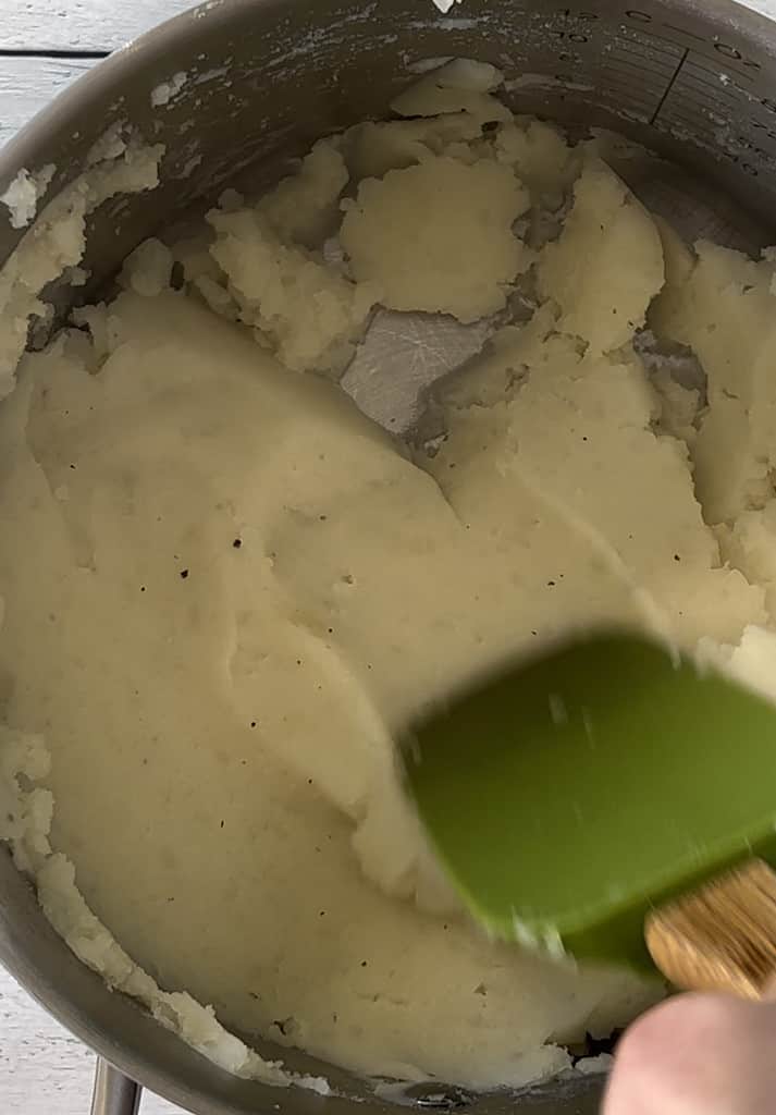 Stirring mashed potatoes in a saucepan.