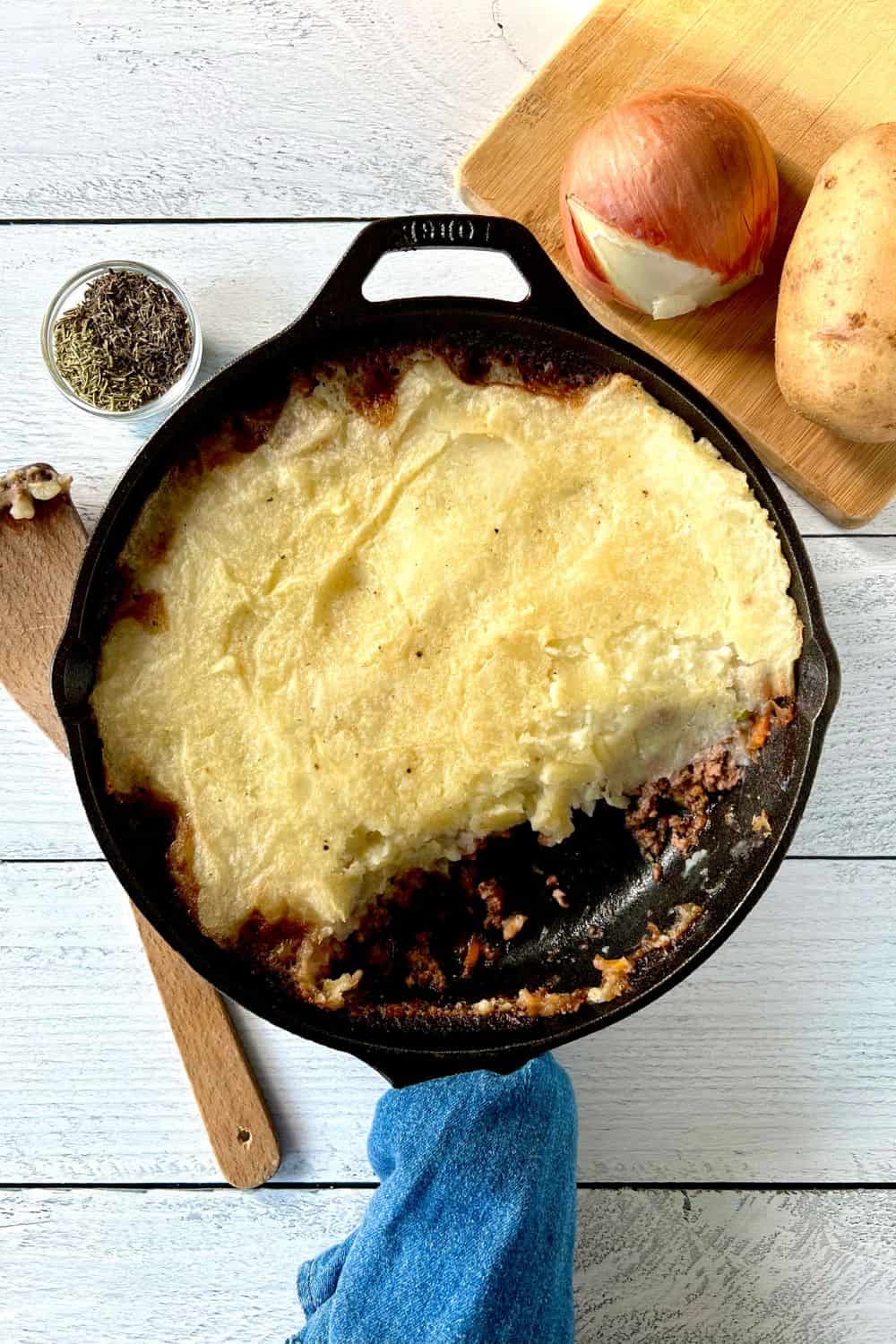 Healthy Shepherd's Pie in a cast iron skillet with a denim towel wrapped around its handle.