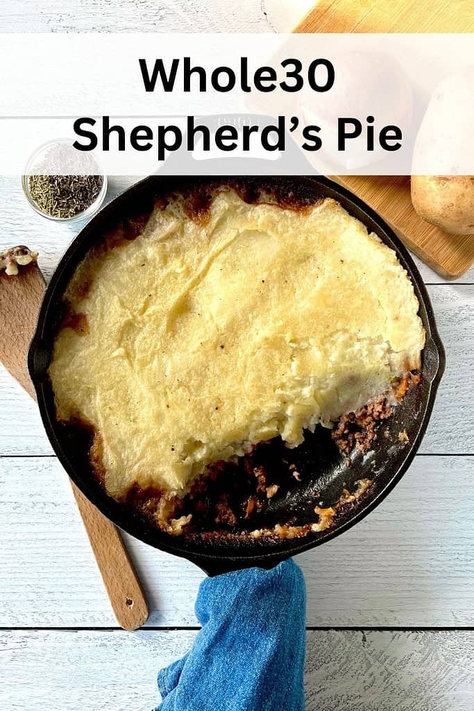 Whole30 Shepherd's Pie in a cast iron skillet with a denim towel wrapped around its handle.