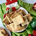 Paleo coconut oil shortbread on a snowman plate on a green napkin surrounded by ornaments and garland.