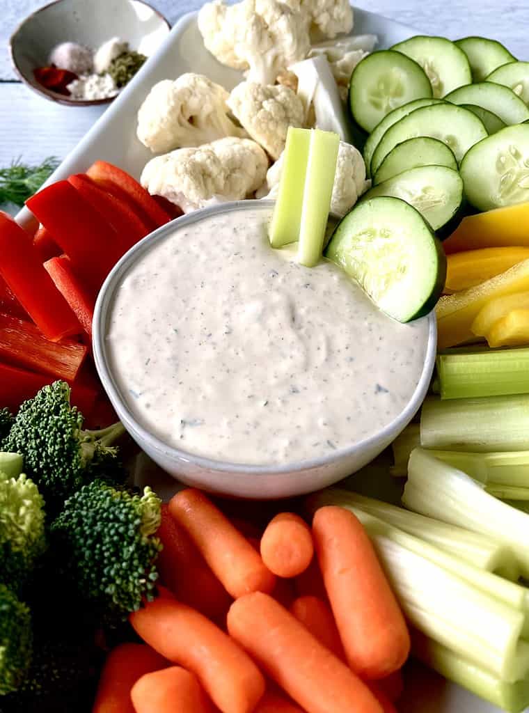 Keto veggie dip in a white bowl surrounded by carrots, celery, broccoli, peppers, cauliflower and cucumber.