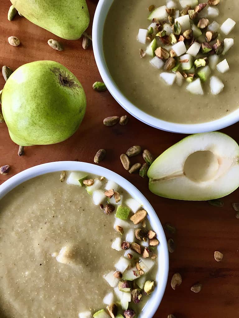 Paleo parsnip soup in 2 white bowls topped with diced pars and pistachios.