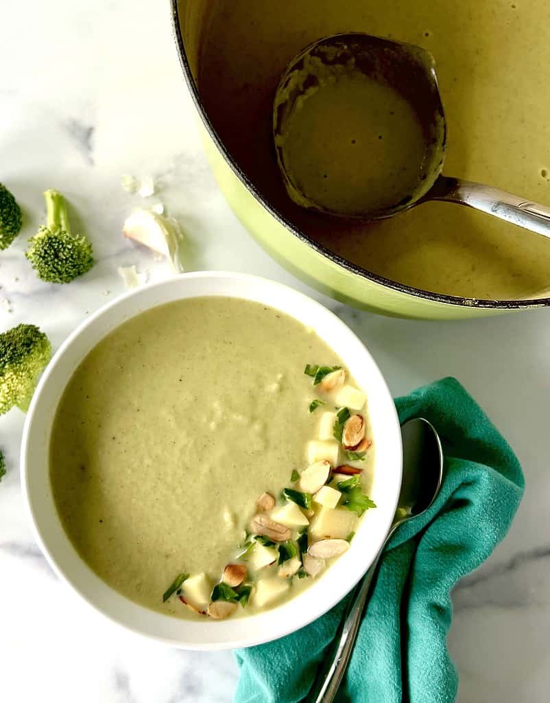Paleo Broccoli Soup in a bowl topped with parsley, diced apples and sliced almonds.