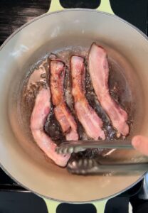 Flipping bacon in a pot.