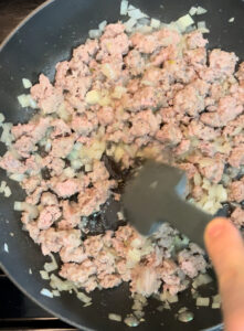 Cooking sausage and onion in a skillet.