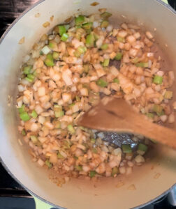 Sauteing onions and celery in a pot.