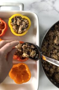Stuffing bell peppers in a white baking dish.
