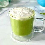 A matcha latte with almond milk in a glass mug.