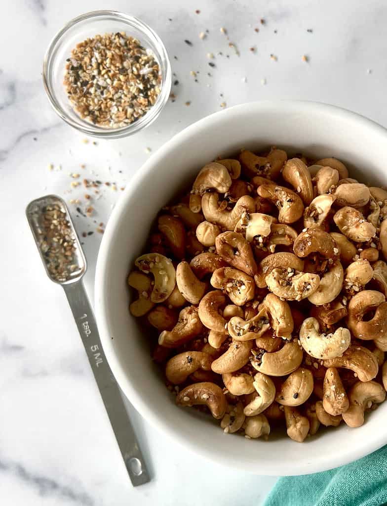 Spiced roasted cashews in a bowl on a marble table.