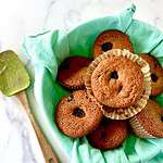 Dairy-free blackberry muffins in a towel-lined bowl next to a spatula with raw batter on it.