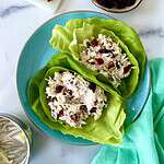 Pecan cranberry chicken salad in lettuce cups on a plate.