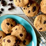Grain-free oatmeal cookies, some with chocolate chips on a blue plate and some with raisins on a cooling rack.