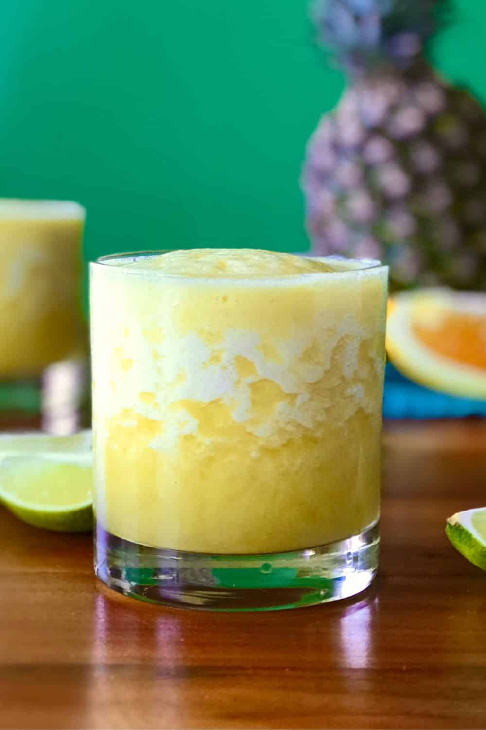 A frozen pineapple mocktail in a glass on a wooden table.
