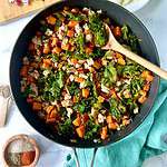 Sweet potato hash with ground turkey and kale in a large skillet with a large wooden spoon.