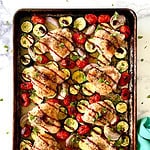 Sheet pan chicken with cherry tomatoes, zucchini and shallots, drizzled with balsamic glaze and sprinkled with fresh basil.