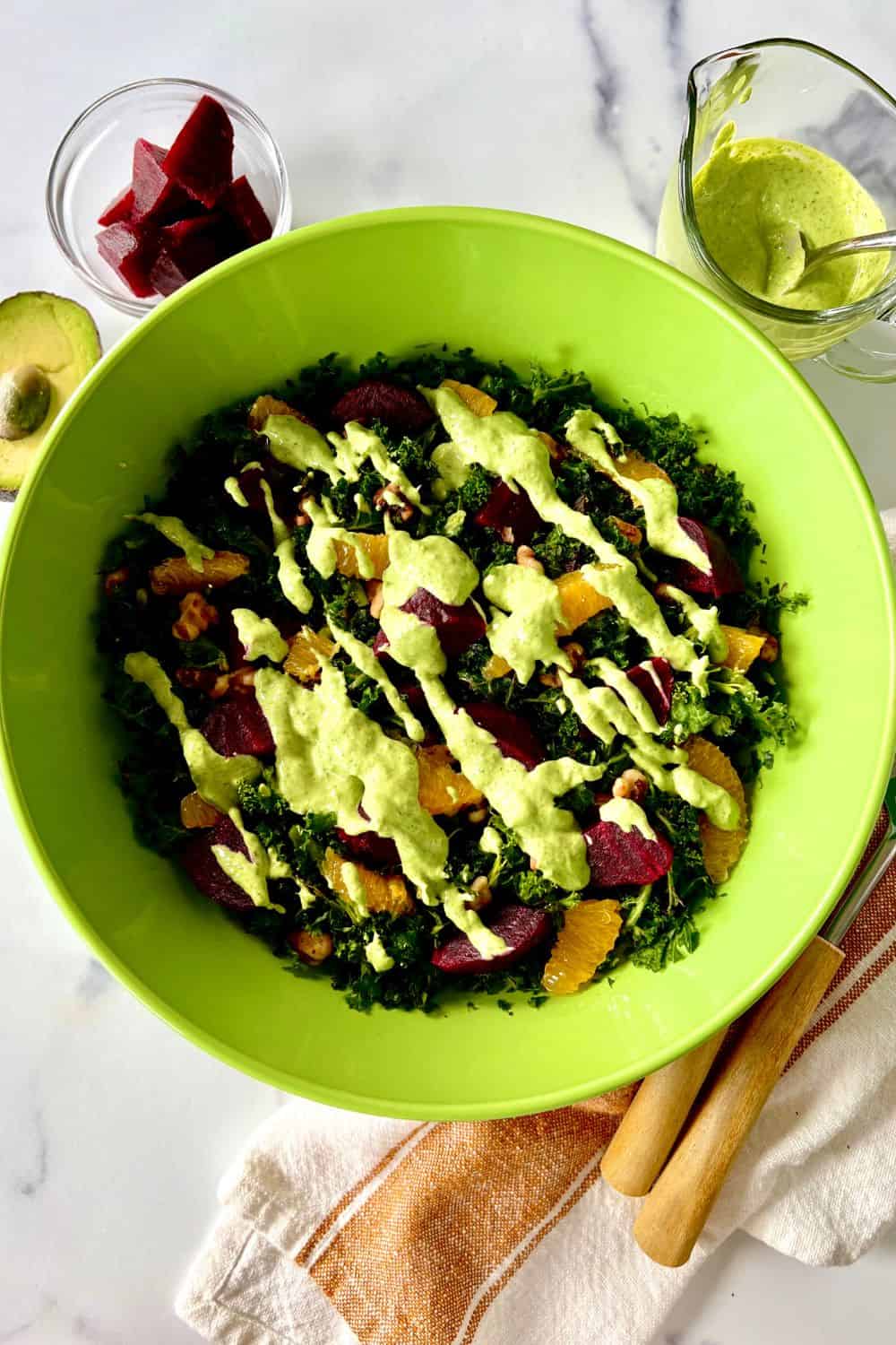 Beet kale salad in a large bowl drizzled with green goddess dressing.