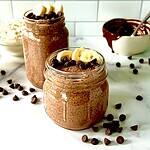 Protein chia seeds pudding made with chocolate chips in mason jars topped with sliced banana and more chocolate chips.