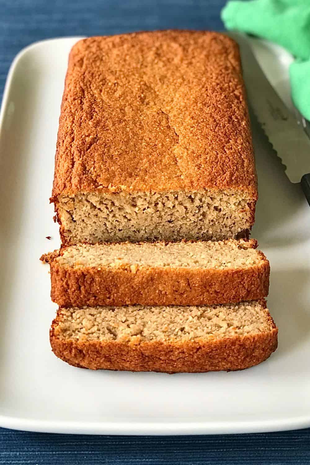 Gluten free and dairy free banana bread sliced on a platter next to a bread knife.