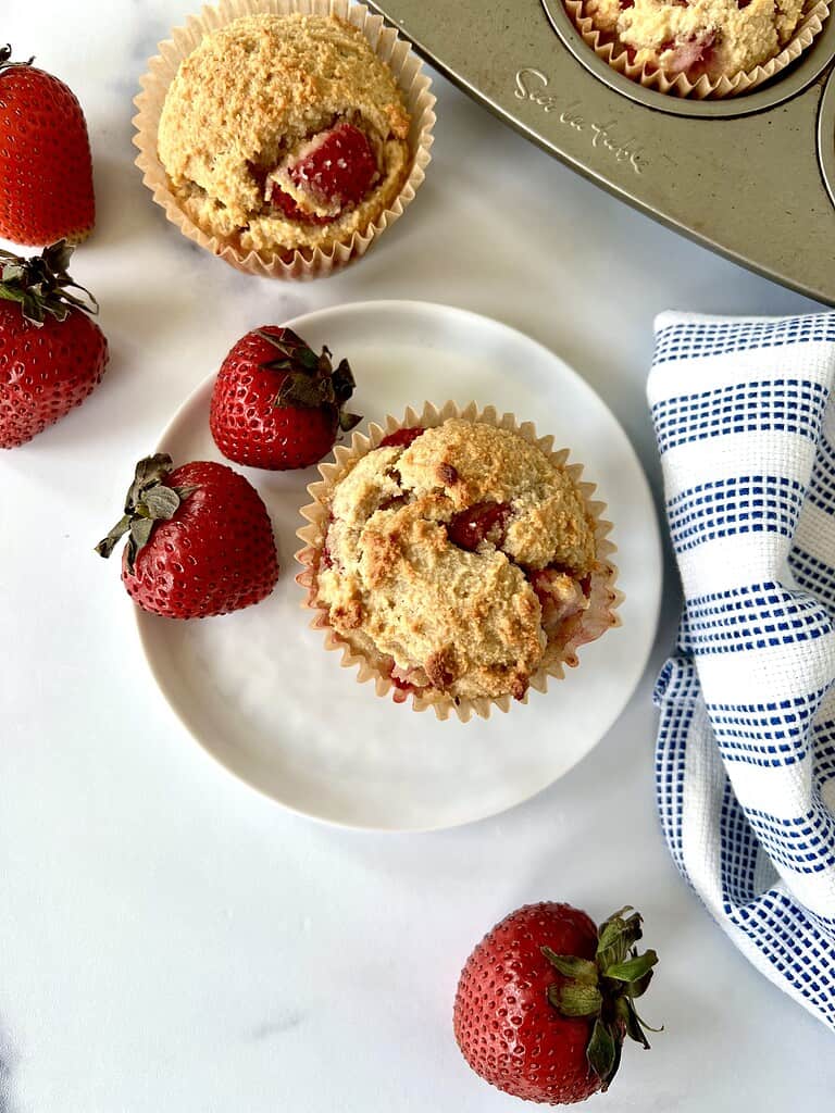 Healthy strawberry muffins in a muffin pan and on a plate strawberries.