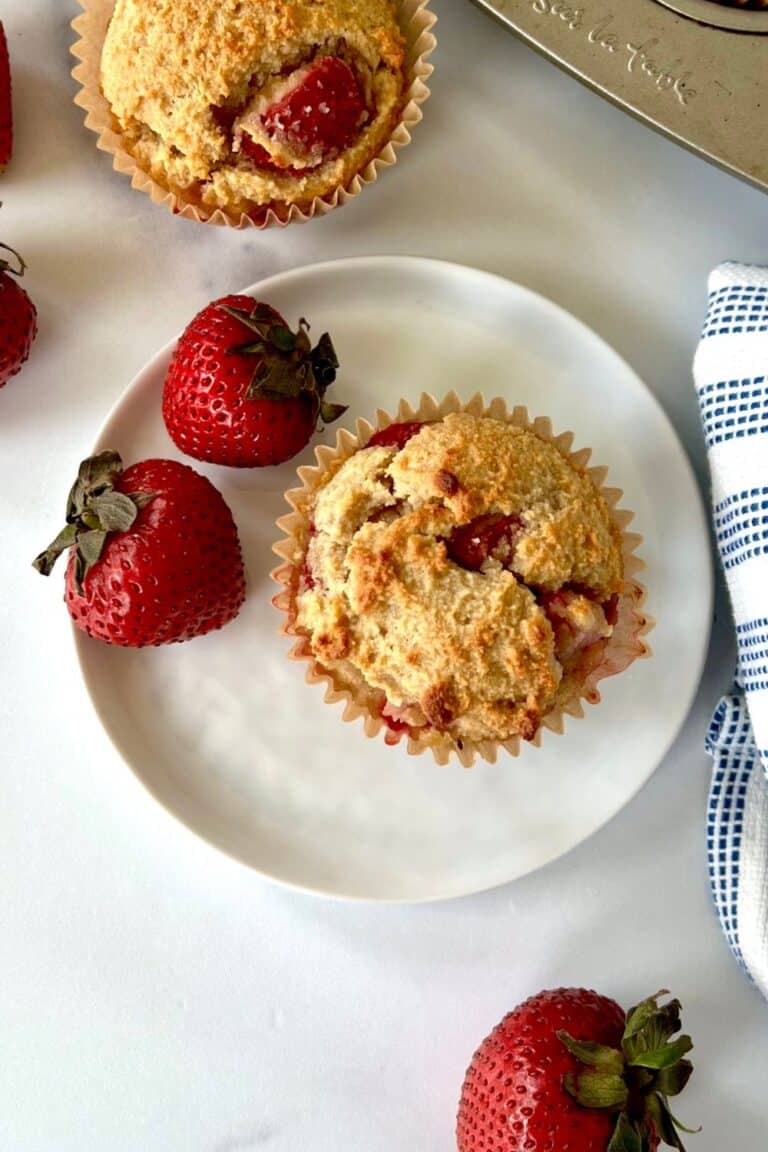 Strawberry Gluten Free Muffins one a plate with fresh strawberries and on a marble surface.