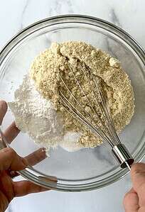 Whisking dry muffin ingredients in a glass bowl.